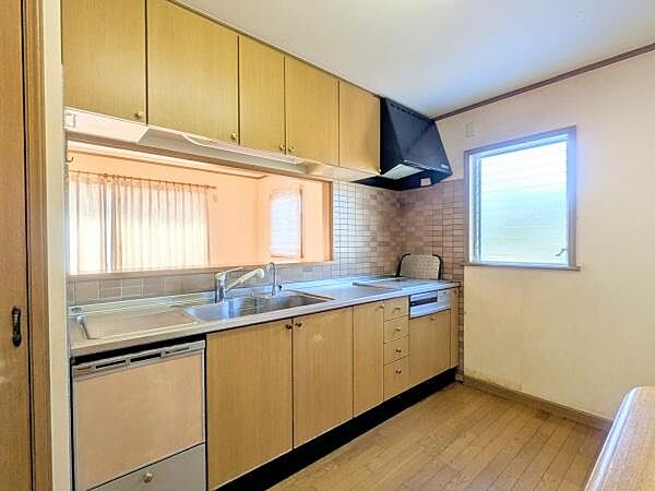 窓から光が差し込む明るいキッチンです。上下に収納が充実しており整理整頓しやすいです。シンクや作業スペースもゆとりがあります。換気扇も設置されていて快適に使えます。