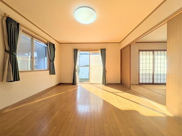 大きな窓が配置されており明るさを感じる洋室です。フローリングがシンプルな印象を演出しています。カーテン付きの二面採光で日中も室内が明るいです。壁のデザインがやわらかい雰囲気をもたらします。