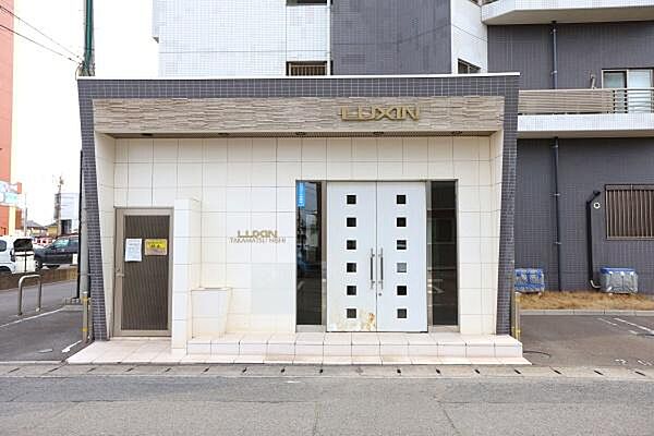 白を基調としたデザインが目を引きます。正面のガラスドアが開放感を演出しています。シンプルな造りで洗練された雰囲気です。建物前のスペースも広々としています。