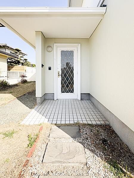 白い玄関ドアが印象的です。タイル張りのアプローチはお手入れが簡単です。屋根付きで雨の日でも安心して出入りできます。