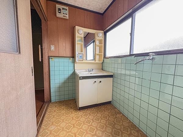 大きな窓があり自然光がたっぷり入る洗面所です。収納棚も備わっており小物の整理がしやすい設計です。落ち着いたタイルと木目調の壁が特徴的でレトロな雰囲気が漂います。