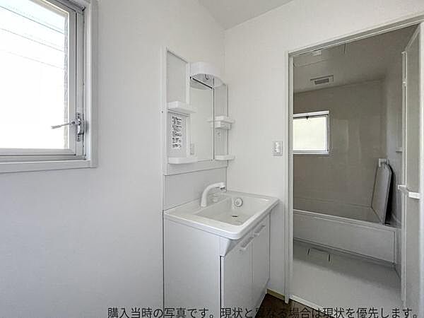 清潔感のある白を基調とした洗面所です。窓から光が差し込み明るい空間が広がります。洗面台は収納付きで小物の整理にも便利です。浴室への動線もスムーズで快適な使い勝手が期待できます。
