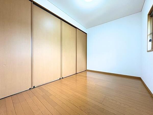明るいフローリングが印象的な洋室です。壁面には大容量の収納スペースを備えています。シンプルな設計で家具の配置もしやすいお部屋です。落ち着いた木目調が空間に統一感を与えています。
