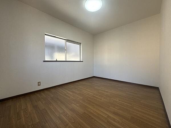 窓から柔らかな明かりが入る洋室です。シンプルな内装で使いやすい空間が広がっています。木目調のフローリングが落ち着いた雰囲気を演出しています。天井照明も備え付けられており明るさも確保されています。