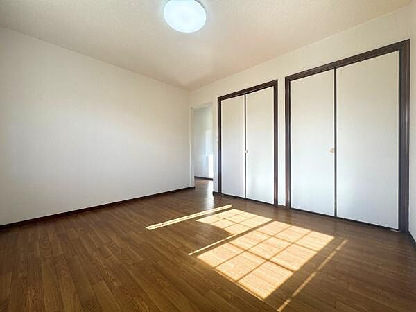 洋室は明るい光が差し込む空間です。ブラウンのフローリングが落ち着いた印象を演出します。収納スペースも充実しておりすっきりとした室内を保てます。扉のデザインが空間にアクセントを加えています。