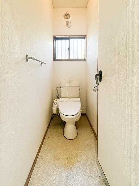 トイレはシンプルな設計で使いやすさが感じられます。窓からは自然光が入るため明るい空間になっています。ペーパーホルダーが壁面に備え付けられており機能的です。
