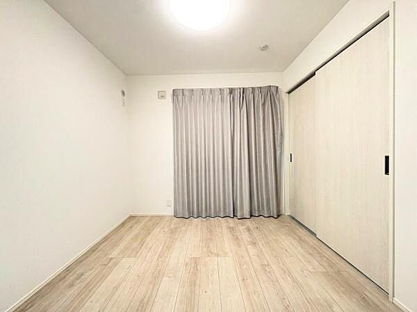 シンプルな内装が特徴的な洋室です。明るい色合いのフローリングが空間を広く感じさせます。大きなクローゼットも設けられています。