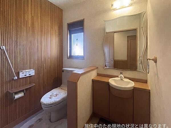 木目調の壁面が温かみを感じさせるトイレです。独立した手洗いスペースも設置されています。収納も備わっているため使い勝手の良い空間です。