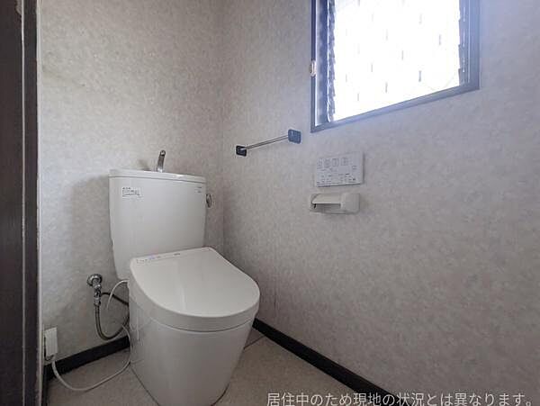窓付きで換気しやすいトイレです。温水洗浄便座を備えており快適にご使用いただけます。壁面に手洗い棚やペーパーホルダーが設置されています。現地の状況と異なる場合があります。