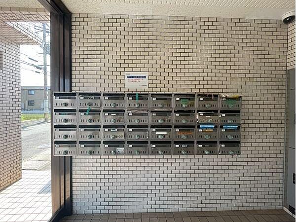 エントランスには複数の郵便ポストが並び使いやすい配置となっています。清潔感のある白いタイルが印象的です。日当たりも良く明るい雰囲気が感じられます。オープンスペースが広がりゆったりとした空間です。