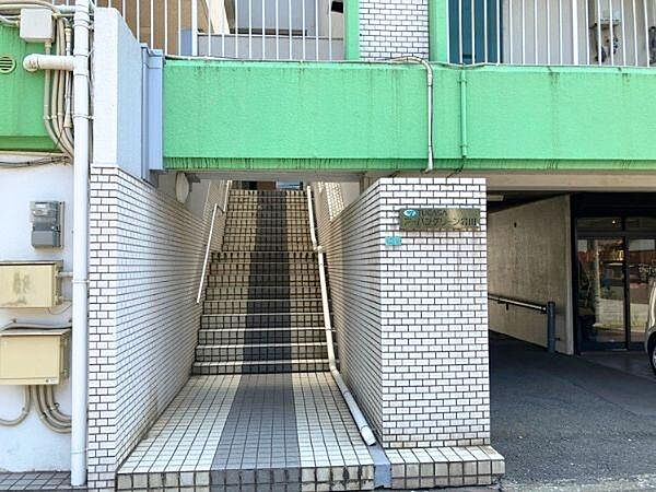 エントランスにはタイル張りの階段があり手すりも設置されています。明るいグリーンのアクセントが印象的です。建物の入り口が屋根付きで雨の日にも便利です。エントランス周辺は整然とした印象です。