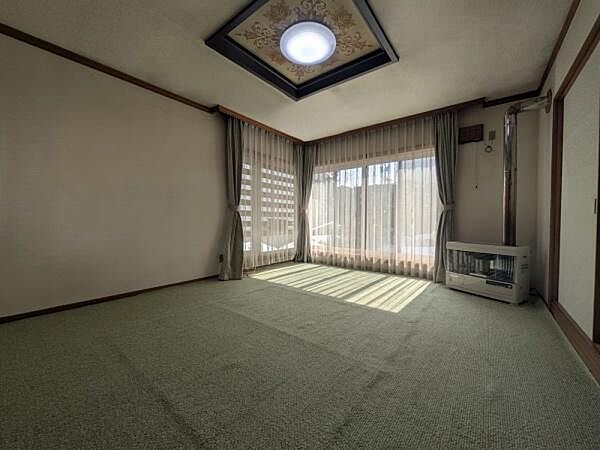 大きな窓から光が差し込む明るいリビングです。壁の色調とカーペットが落ち着いた雰囲気を演出しています。広々とした空間がありリラックスした時間を過ごせます。