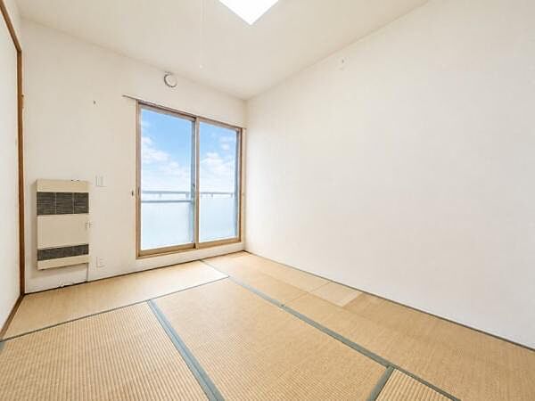 明るい日差しが差し込む和室です。大きな窓からは空の景色も楽しめます。シンプルな造りで落ち着きのある空間です。床には畳が敷かれておりくつろぎやすい雰囲気です。無駄のないレイアウトが魅力的です。