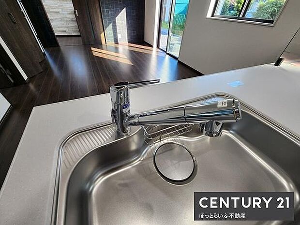 窓からの光が差し込む明るいキッチンです。シンプルなデザインのシンクが使いやすそうです。作業スペースも広く確保されています。水栓は手入れがしやすい仕様です。隣室との一体感も感じられます。