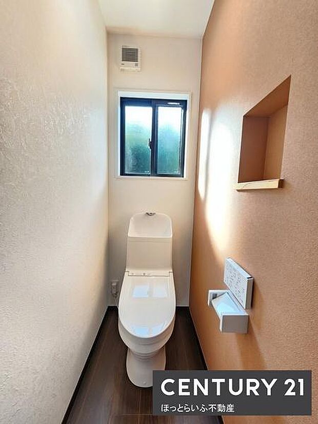 窓付きのトイレでしっかり換気ができて快適です。壁の一部には棚スペースがありちょっとした収納に便利です。すっきりとした内装で清潔感のある印象です。ペーパーホルダーとリモコンタイプの洗浄機能付きです。