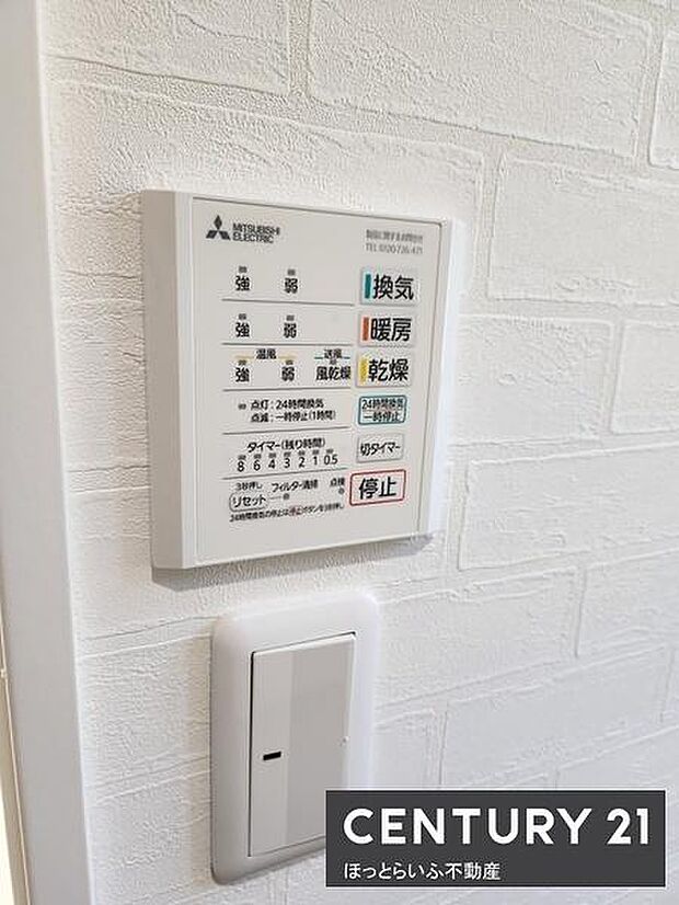 浴室暖房乾燥機の操作パネルが壁に設置されています。シンプルで見やすいデザインです。操作がしやすい位置にあり日常の使い勝手に配慮された設備です。壁紙の質感も感じられる空間です。