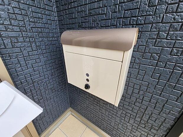 シンプルなデザインのポストが設置されています。壁面にしっかりと固定されており独立したスペースです。出し入れしやすい位置に設置されています。清潔感のあるカラーも特徴です。