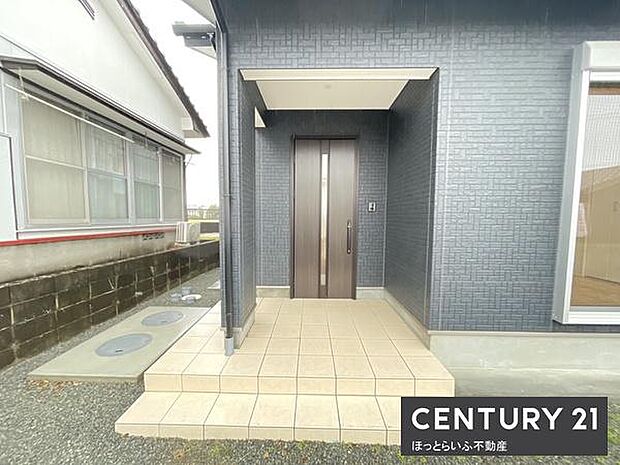 シンプルで清潔感のある玄関アプローチが印象的です。屋根付きで天候にも配慮されています。段差が低めで使いやすい設計です。落ち着いた色合いの外壁が周囲と調和しています。