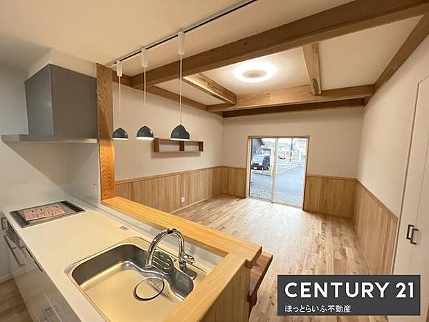 木目を活かした温かみのあるキッチンです。ダウンライトが明るさをしっかり確保しています。カウンタータイプで開放感のある空間です。IHクッキングヒーターを備えています。シンク周りも使いやすい設計です。