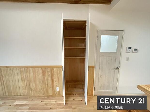 シンプルで使いやすい収納スペースが配置されています。可動式の棚が設けられており高さに合わせた整理が可能です。木目調の内装と一体感のあるデザインが特徴です。収納扉はホワイトカラーで空間に調和しています。