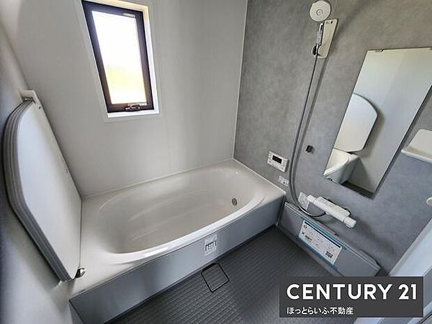 窓付きで明るさを感じられるバスルームです。壁や床の色合いが落ち着いた印象を与えます。浴槽はゆったりとしたサイズ感です。換気にも配慮された造りが感じられます。清潔感のある空間です。