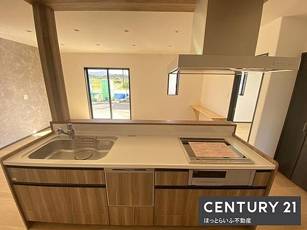 広々としたリビングが魅力的です。大きな窓からは明るい陽射しが差し込みます。キッチンカウンターが空間に開放感を添えます。シンプルな内装で使いやすいレイアウトです。落ち着いた色合いが印象的です。