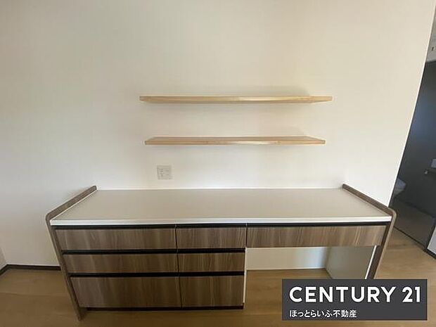 シンプルなデザインのカウンターと棚が設置されております。空間を有効活用できる造りとなっています。収納スペースが確保されています。落ち着いた色合いが印象的です。