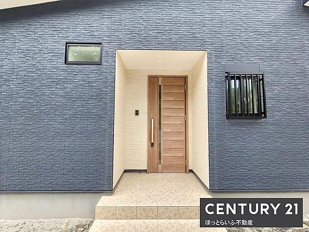 シンプルながらも洗練されたデザインの玄関です。木目調のドアがアクセントになっています。モダンな外壁と調和しています。小窓が程よい採光を確保しています。