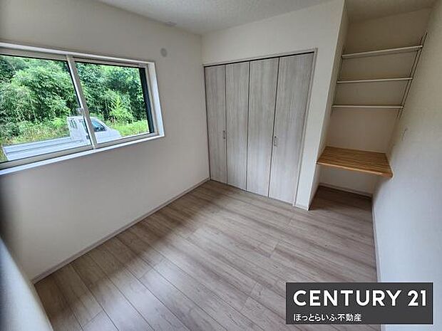 大きな窓から自然の光が差し込む明るいリビングです。床や収納のカラーが統一され落ち着いた雰囲気が漂います。クローゼットと棚付きのスペースがすっきりと整った印象を与えます。