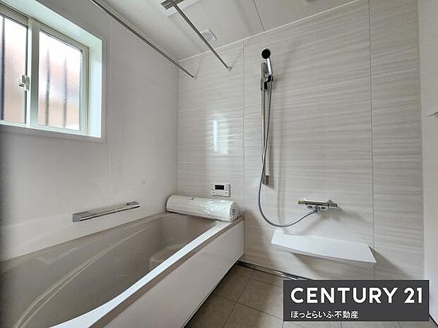 窓から自然光が差し込む明るいバス空間です。浴槽はゆとりあるサイズ感で毎日のリフレッシュに適しています。白を基調とした内装が清潔感を演出しています。モダンなデザインのシャワーも特徴です。