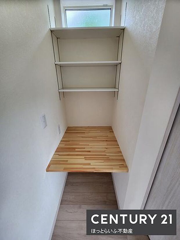 棚とカウンターが設けられた収納スペースです。上部の棚は小物の収納に便利です。自然光が入る窓も備えています。シンプルな内装で使いやすさが特徴です。壁面を活用でき整理整頓がしやすい収納です。