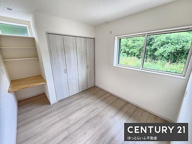 明るい光が差し込む洋室です。収納スペースがしっかり確保されておりすっきりとした印象です。デスクや棚も設けられており使い勝手にも配慮されています。落ち着いた色合いの床が室内を優しく演出しています。