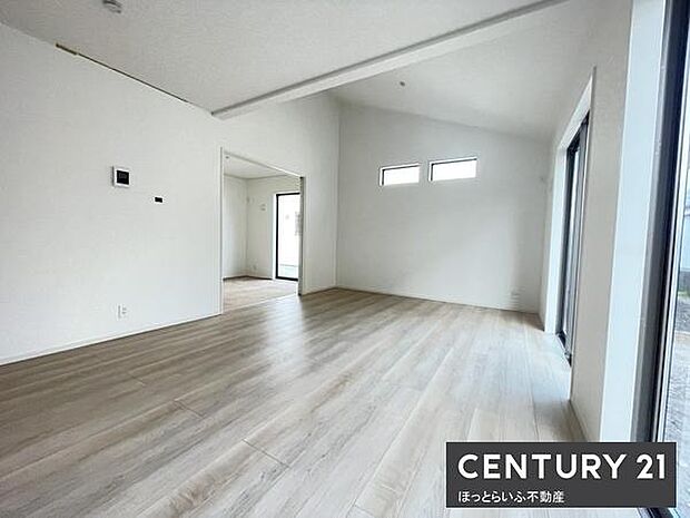 リビングには大きな窓があり自然光がたっぷりと差し込みます。白を基調とした内装で明るく開放的な雰囲気です。床材はナチュラルな色合いで家具の配置がしやすい空間となっています。シンプルなデザインが特徴です。