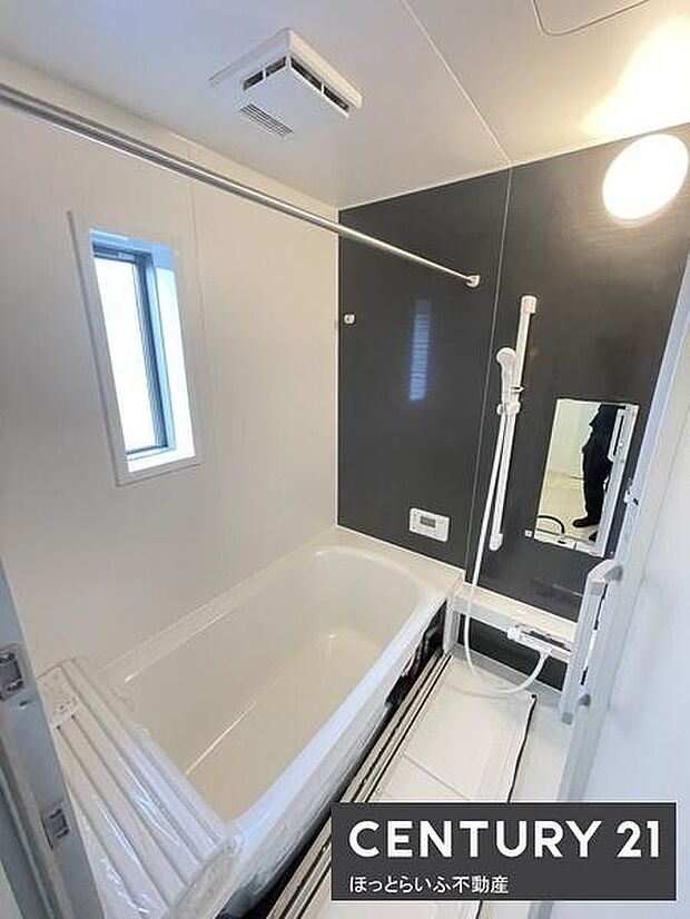 浴室内に窓があり換気がしやすい造りです。黒と白のコントラストが印象的な内装です。手すり付きで安心感があります。鏡や収納スペースも充実しています。明るい照明で清潔感を感じられます。
