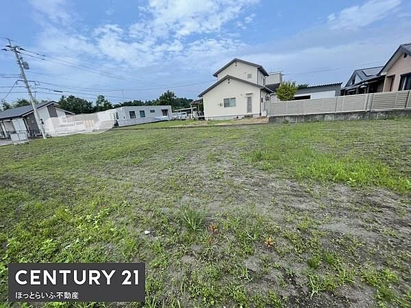 広々とした現地土地写真です。周囲には住宅も点在し開放感が感じられます。平坦な地形のためさまざまな用途に適しています。道路へのアクセスもしやすい立地です。周辺には落ち着いた住宅街が広がっています。
