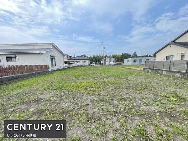 開放感のある現地土地写真です。空が広がり周囲には住宅が立ち並ぶ落ち着いた環境です。整った形状で利用しやすい印象です。前面道路へのアクセスも良好です。