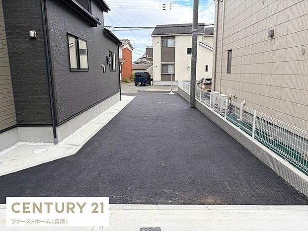 前面道路がしっかり舗装されており車両の出入りがしやすい現地写真です。安心感のある幅の道路が続いています。隣接する建物との距離感が分かりやすく敷地の雰囲気を確認できます。