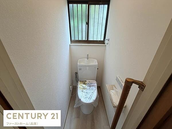 窓付きで換気がしやすいトイレです。明るい自然光が入り清潔感のある空間となっています。手すりも設置されており使いやすさに配慮されています。温水洗浄便座が備わっている点もポイントです。