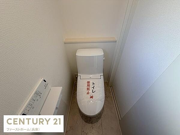 シンプルなデザインのトイレが設置されています。壁紙や床材も明るい色味で圧迫感を感じにくい空間です。アクセントとなる棚が付いておりちょっとした物を置くこともできます。