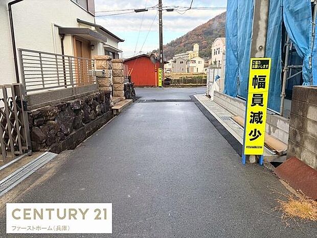 現地前面道路は舗装されておりすっきりとした印象です。周囲には住宅が立ち並び落ち着いた景観が広がっています。視界が良好で車両の出入りも安心です。道幅が狭くなる箇所には案内標識が設置されています。