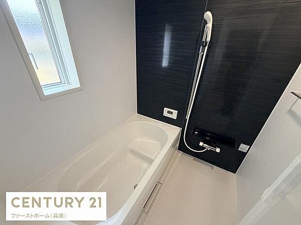 窓から自然光が差し込むため明るい雰囲気のバス空間です。清潔感のあるシンプルな配色で落ち着いた印象があります。壁面は黒を基調としておりモダンなデザインです。シャワー設備も整っています。