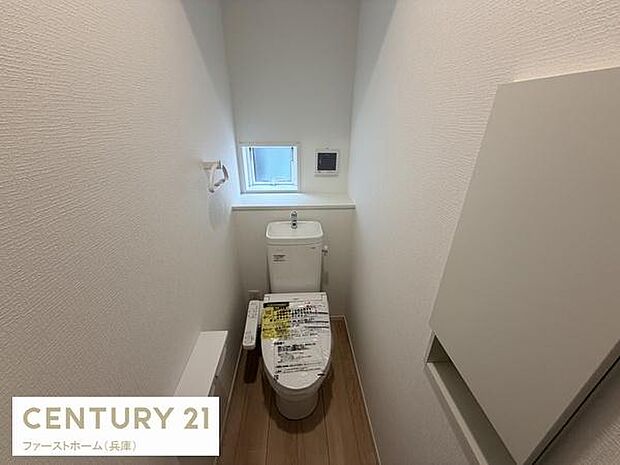 窓が設けられており明るさが感じられるトイレです。コンパクトながらも清潔感のある空間になっています。備え付けの収納があり使い勝手にも配慮されています。壁面の淡い色合いが落ち着いた雰囲気を演出します。