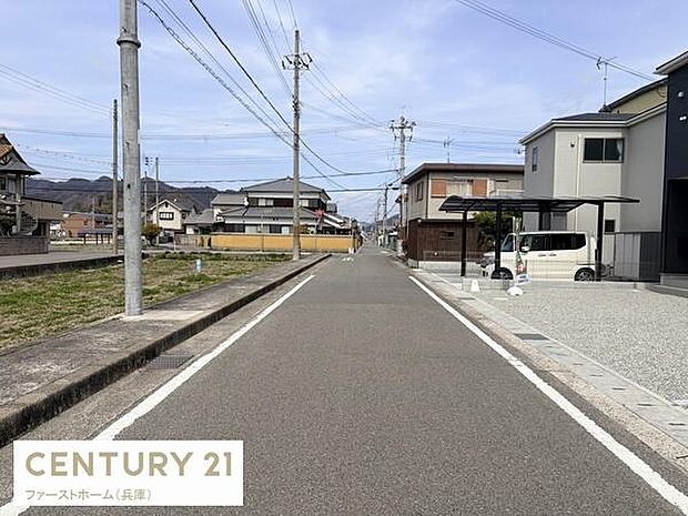 前面道路は広々とした印象で車の出入りがしやすい環境です。周囲には住宅が立ち並び整然とした街並みが広がっています。電柱や街路の配置もすっきりしていて全体的に落ち着いた景観となっています。