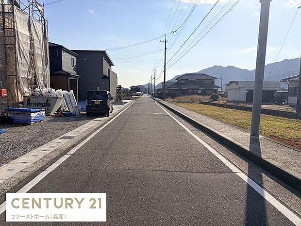 前面道路が広がる開放感のある立地です。周囲は住宅と自然が調和した落ち着いた雰囲気です。車の通行や駐車もスムーズに行えます。陽当たりにも配慮された現地写真となっています。