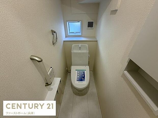 清潔感のあるトイレ空間です。小窓付きで換気がしやすい設計となっています。壁付けの収納も備え付けられています。落ち着いた色合いの内装が特徴です。