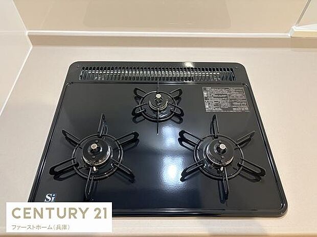 3口タイプのガスコンロが設置されているキッチンです。シンプルで使いやすいデザインが特徴的です。黒色の天板が空間にすっきりとした印象を与えます。お手入れのしやすさにも配慮された仕様です。
