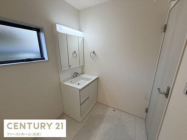 洗面台はシンプルで落ち着いたデザインです。壁に付いたミラー付き収納が便利です。明るい窓が設置されており空間に開放感があります。清潔感を感じる洗面所です。