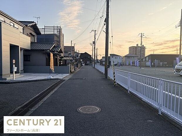 前面道路はしっかりと舗装されており歩道も整備されています。周囲には建物や施設も点在しており落ち着いた街並みが広がっています。道路幅もあり車の通行にも配慮されています。