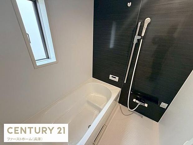 窓付きで換気性の良いバスルームです。ブラックのアクセントパネルがシックな印象を与えます。バスタブとシャワースペースがゆったり設計されています。使いやすい水栓が壁付けで配置されています。