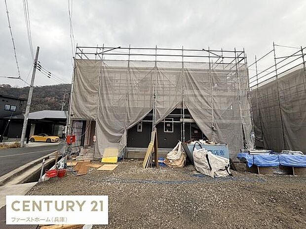 現在建築中の外観です。足場や養生シートがしっかり設置され工事の様子がうかがえます。周辺は住宅が並び前面道路も広めです。完成後の姿が楽しみな一棟です。